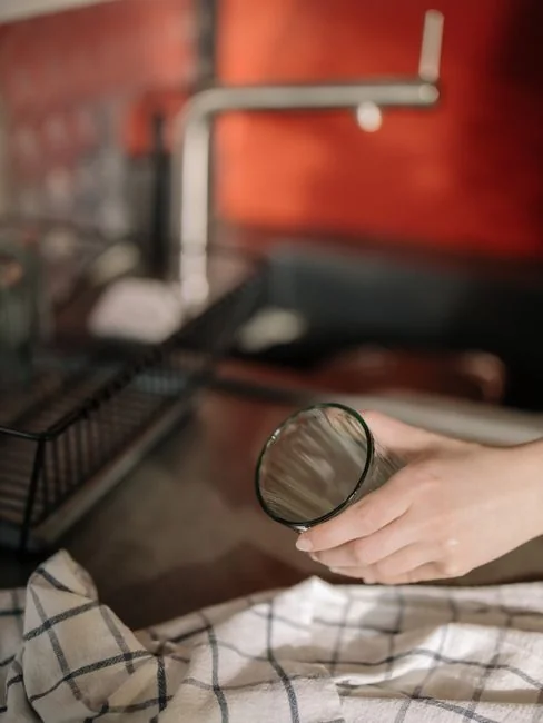 why-choose-us Close-up of hand cleaning window with squeegee outdoors using yellow gloves.